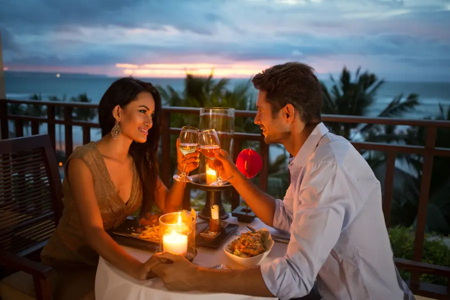 Valentines date ideas with a man and woman having dinner outside on a balcony.